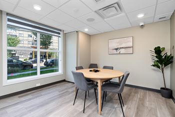A conference room with a table, chairs, and a plant.